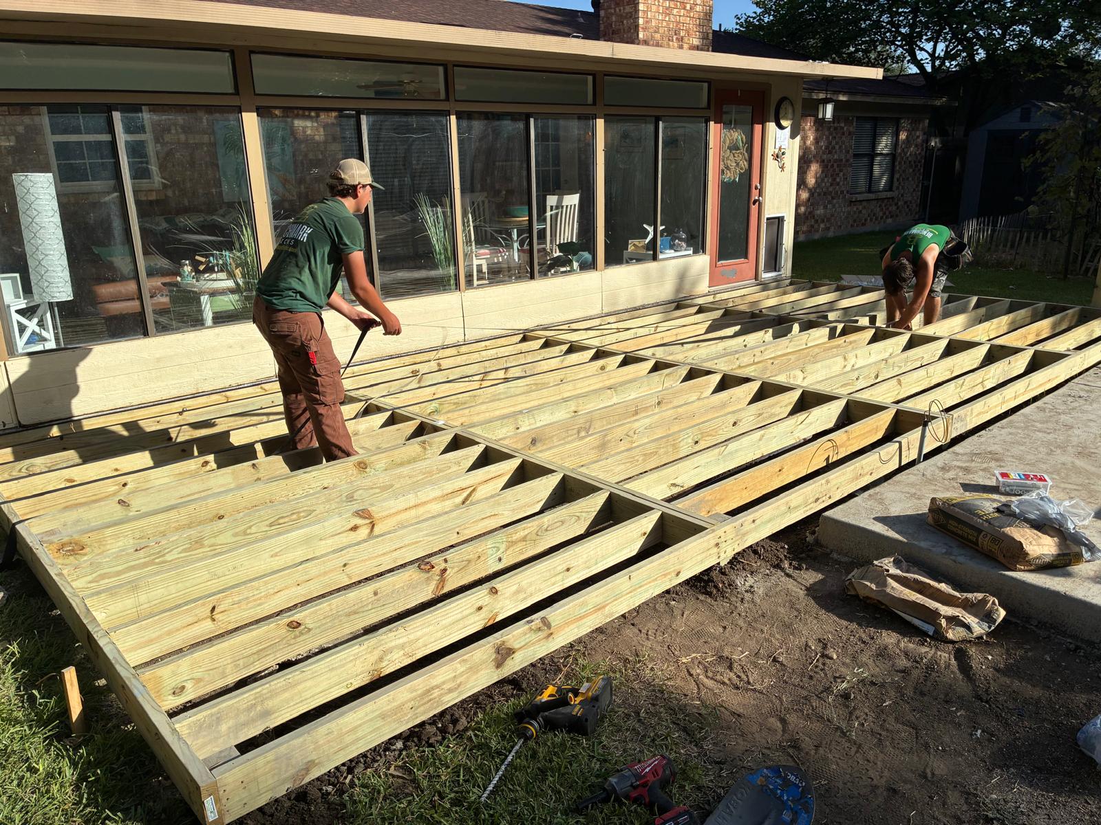 Crew rolling butyl tape along the tops of the joists on Danny's deck frame