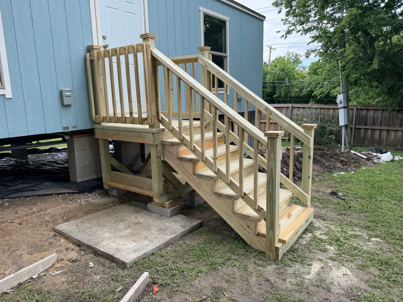 Pressure-treated entry landing and stair run on a blue mobile home