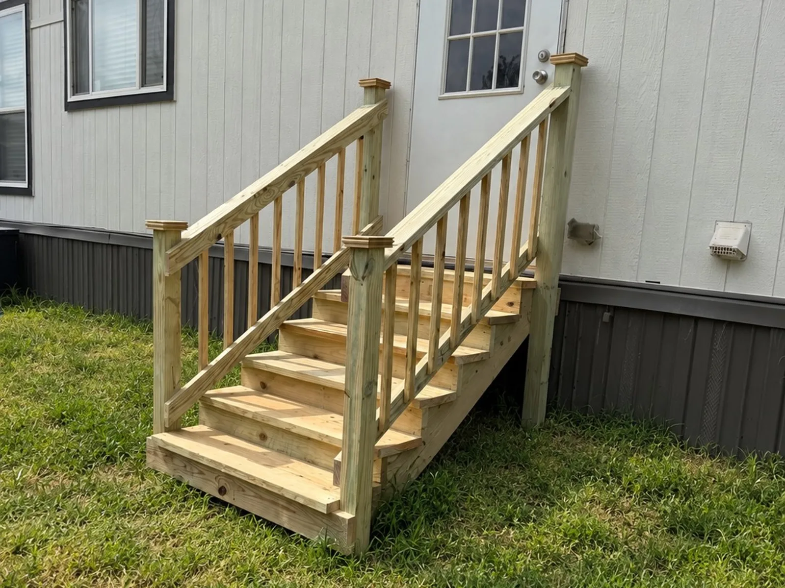 Pressure-treated wood steps with railings at a mobile home door, built by BenchMark Decks