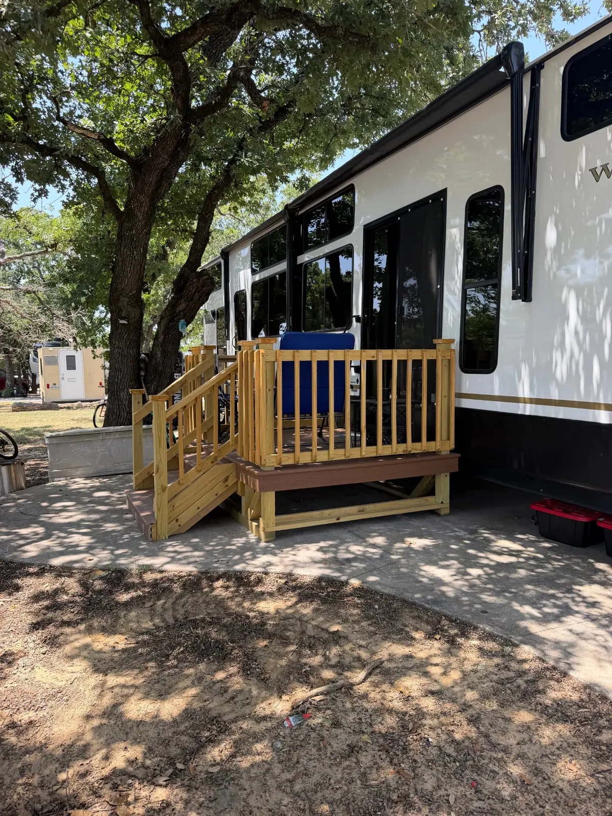 Freestanding RV deck with railing and stairs beside a travel trailer