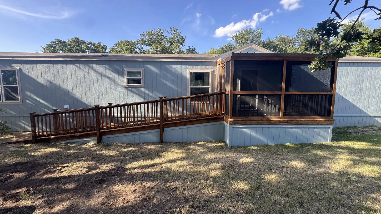 Stained pressure treated back deck with screened porch and spindle railing on a mobile home, built by BenchMark Decks in Cleburne, Texas
