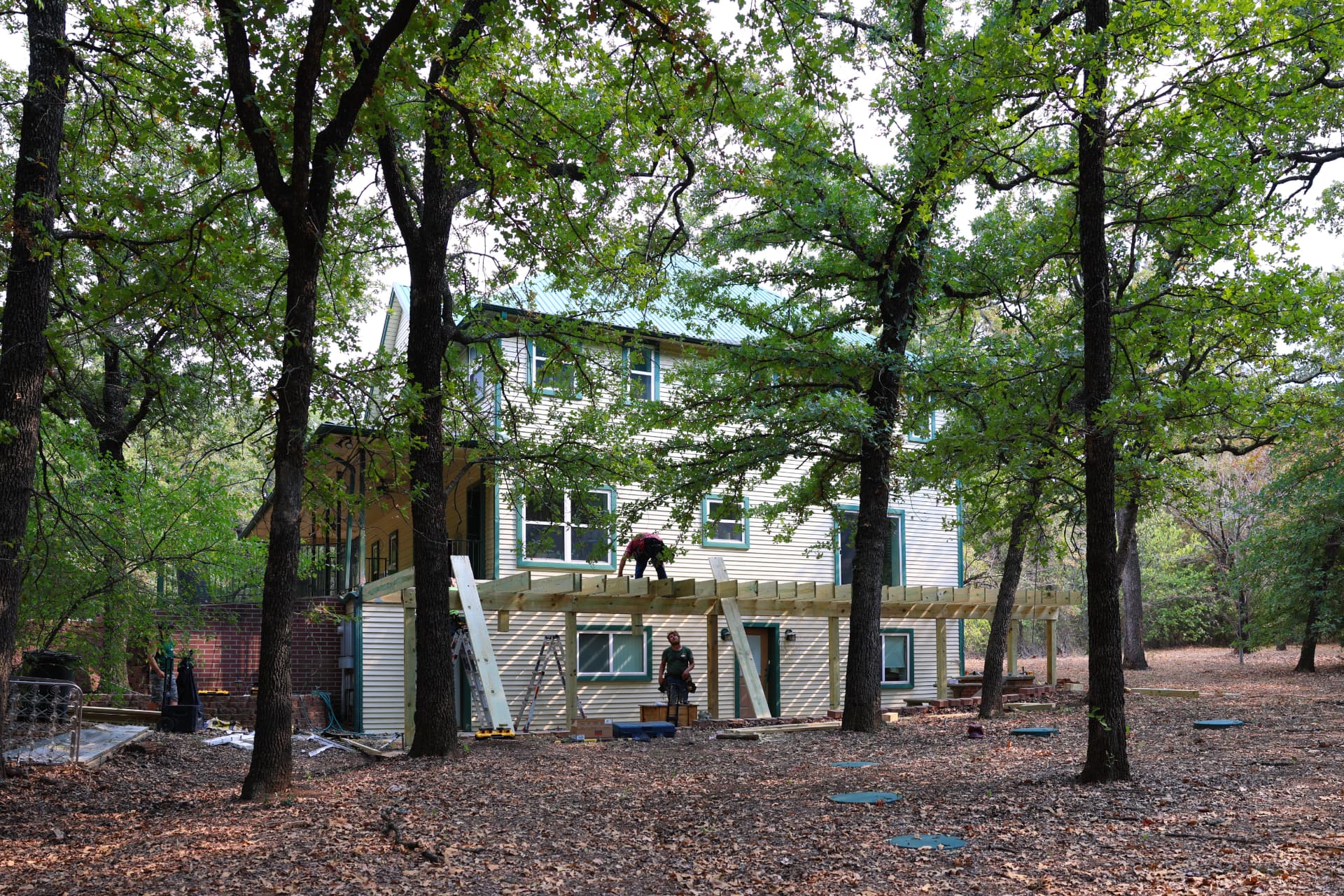 Wide view of Greg's Grandview, TX home with new deck framing going up under the oak trees