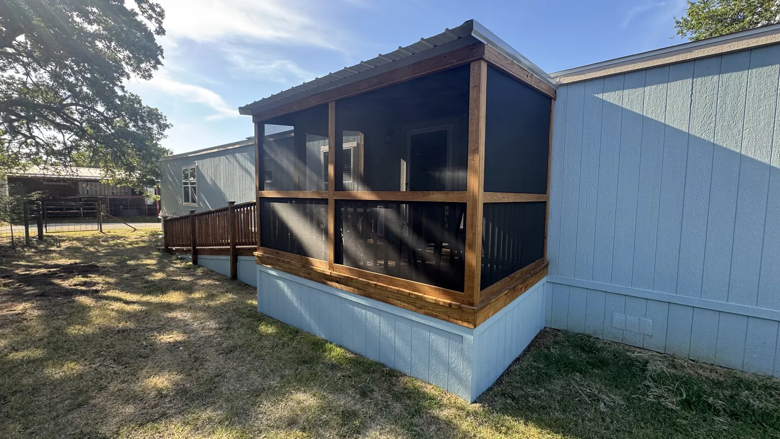 Screened porch deck with metal roof and wood skirting on a mobile home, built by BenchMark Decks in Cleburne, Texas