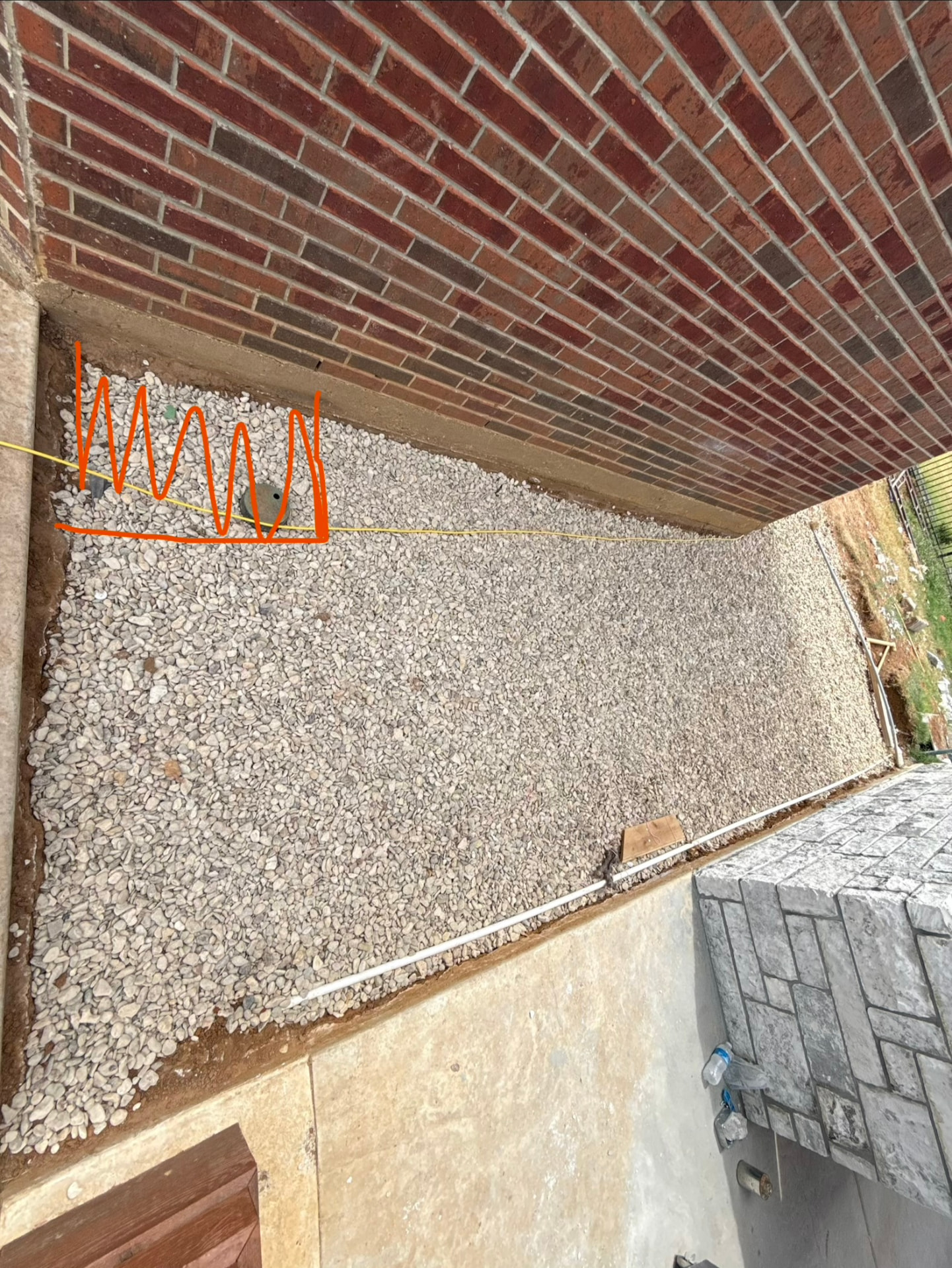 Gravel pad prepped alongside the brick house before Chase's deck framing began