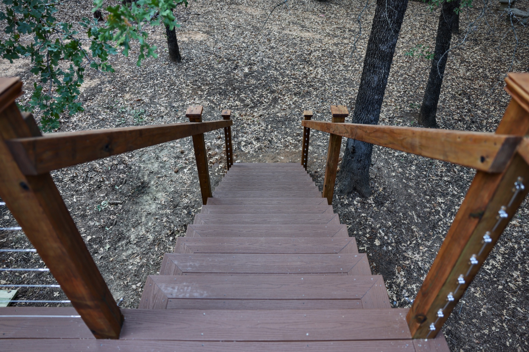 Composite stair treads with cable railing looking down into the tree line