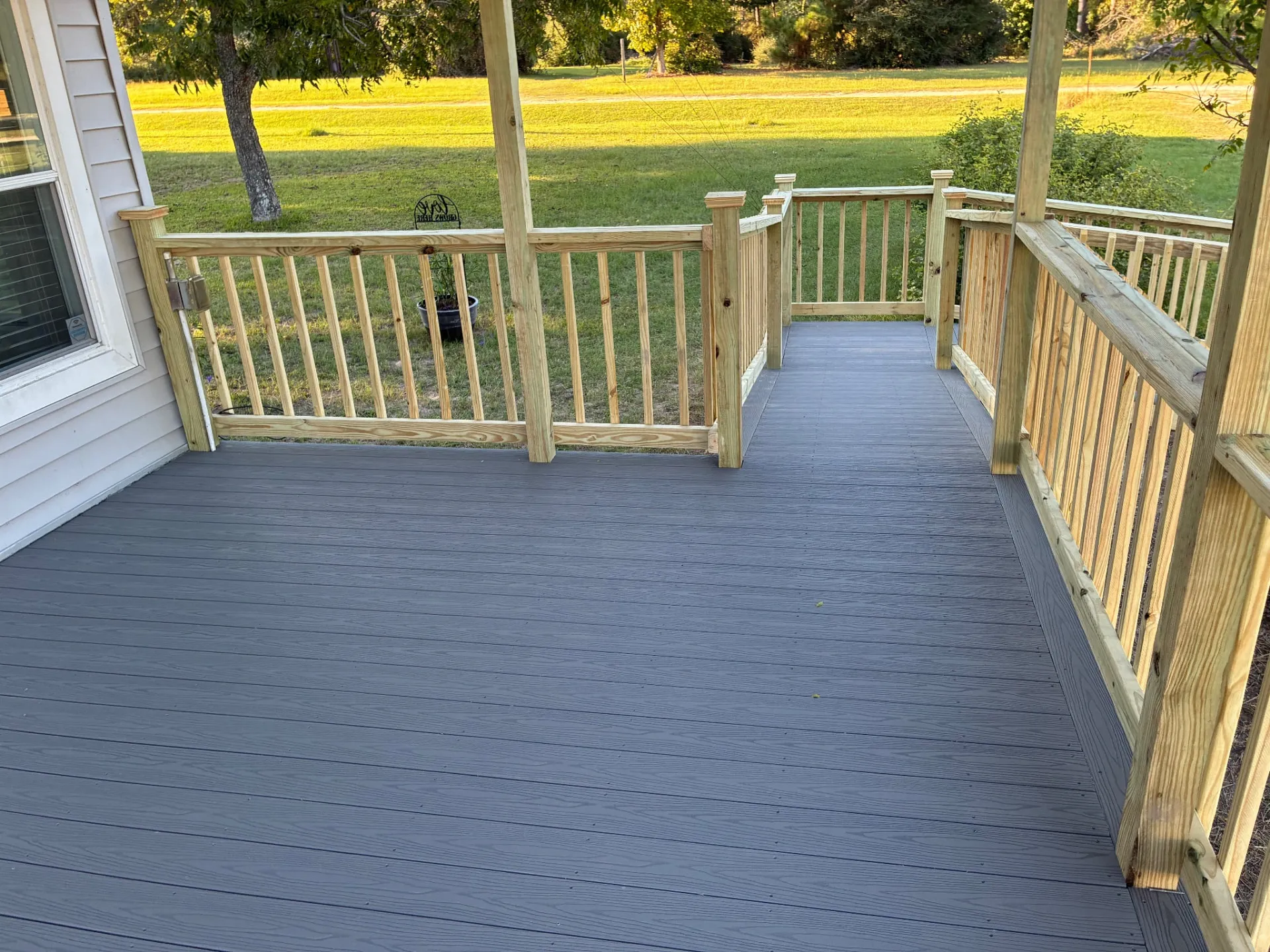 Fiberon Cottage composite deck boards under the covered entry with spindle railing, built by BenchMark Decks in Trinity, Texas