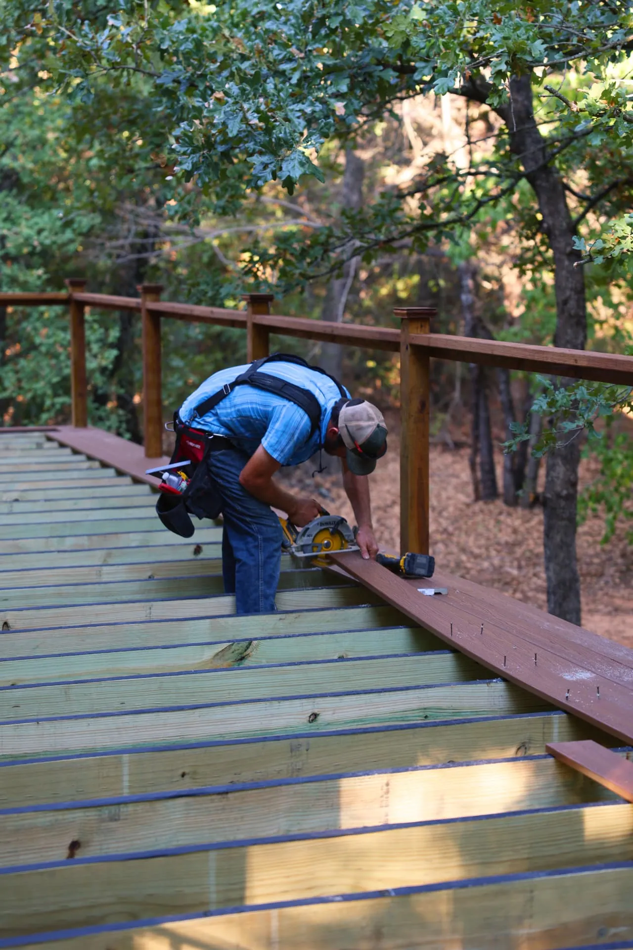 Installer cutting Fiberon Good Life Cabin composite deck boards in place on Greg's Grandview, TX deck