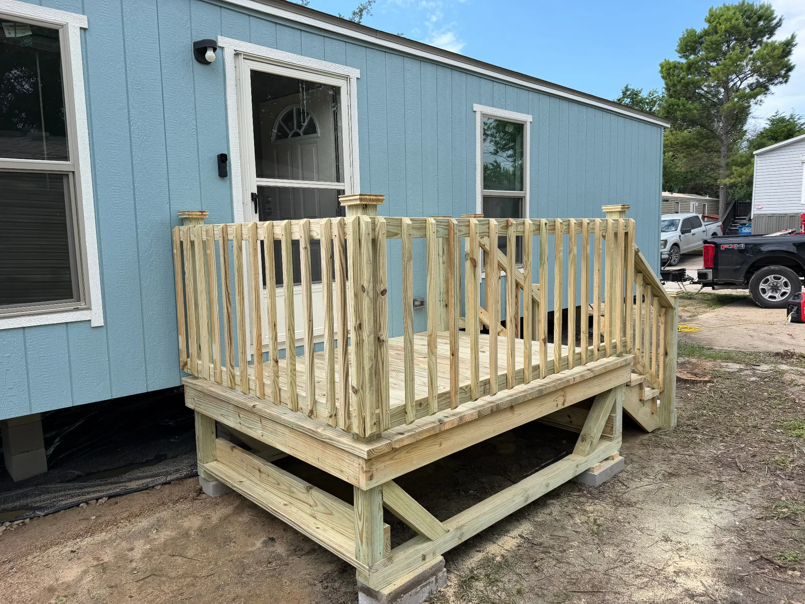 6x8 pressure treated entry deck with wood railing and steps on a manufactured home, built by BenchMark Decks in Dallas, Texas